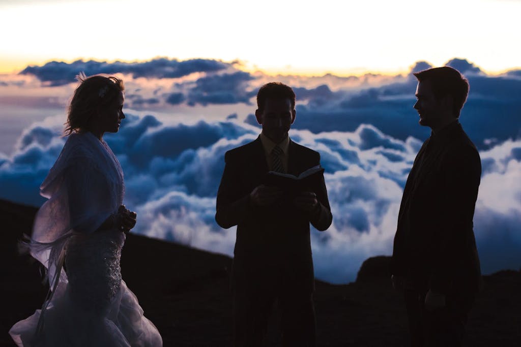 Officiant married bride and groom on mountain above the clouds.