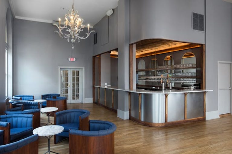 Modern bar with silver around and small tables with circular blue chairs