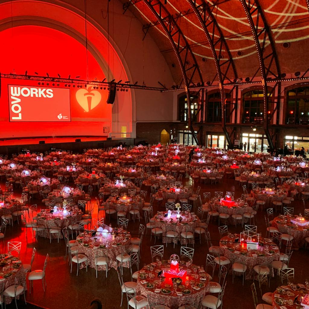 Large ballroom with banquet tables and red uplighting.
