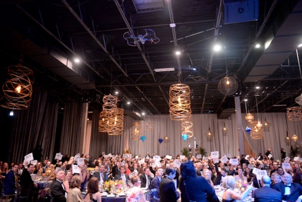 People at seated dinner reception with gold-spiral lighting suspended overhead.