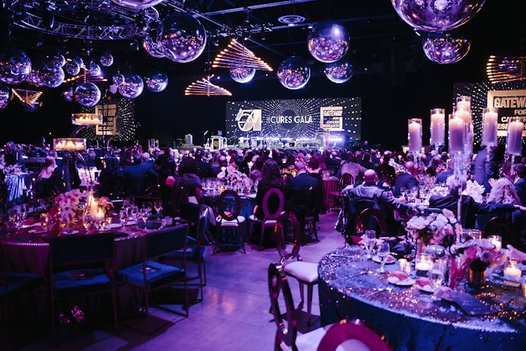 Ballroom with disco balls, purple uplighting, and candle-lit banquet rounds.