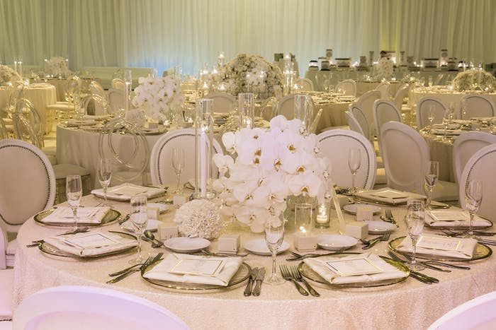 Many round tables in a event space with short orchid wedding centerpieces