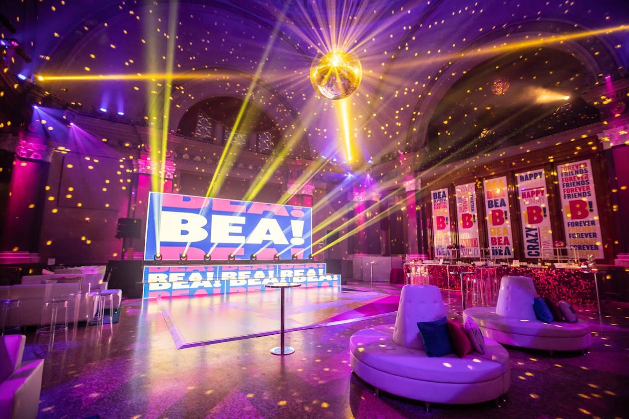 Bat Mitzvah dance floor with gold disco ball and laser lighting, gold-dot projection mapping, and pink-and-purple uplighting.