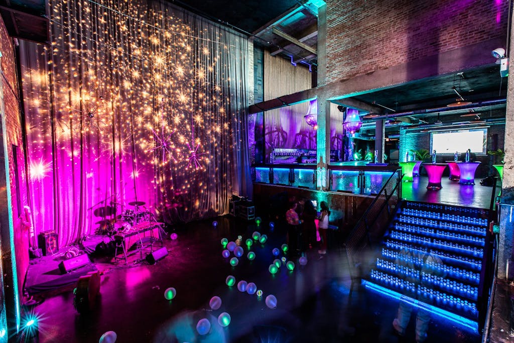 Industrial space with blue and pink uplighting and gold-sparkle ceiling installation.