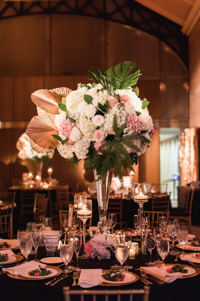 A floral arrangement with gold leaves and pink and white florals sits high above a seating arrangement
