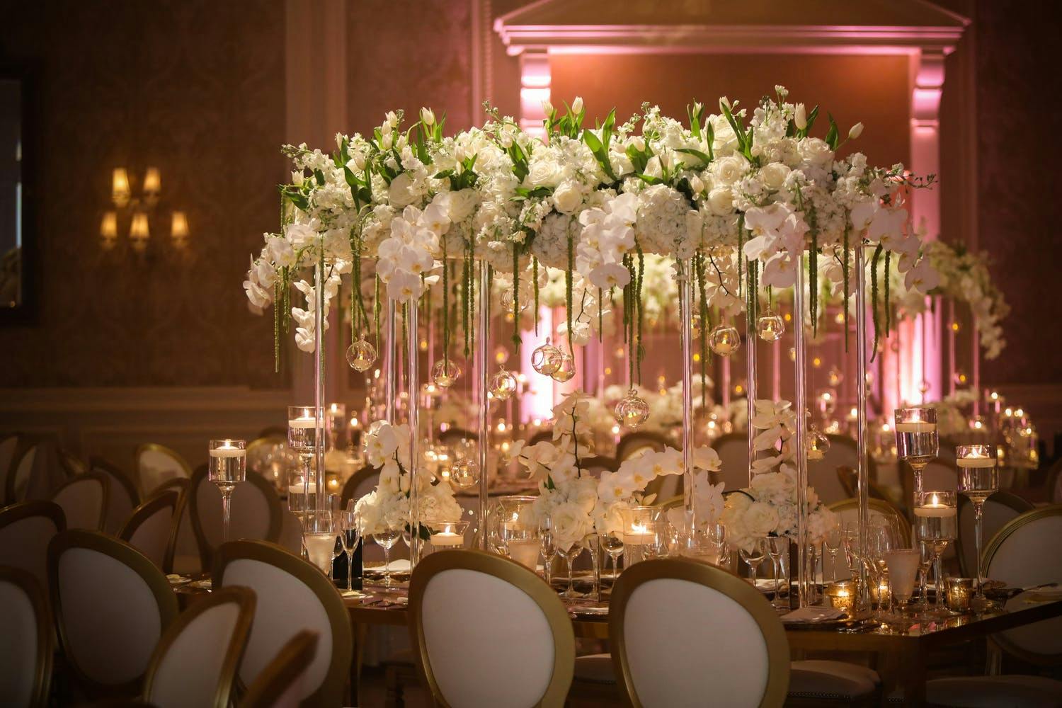 White orchid wedding with centerpiece featuring a bridge of tall, clear vases and an arc of white orchids.