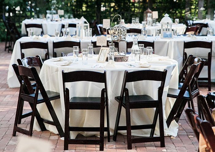 Round tables with black wooden folding chairs. Hanging lanterns are at the center of each table