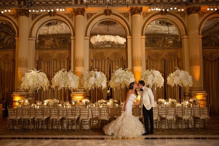 Massive white orchid wedding centerpieces in the background of a couple with archways