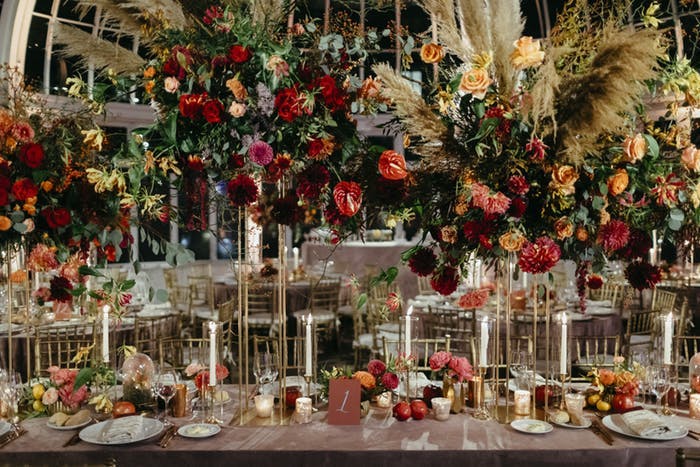 tall multi colored florals lifted with gold stems and white candlesticks