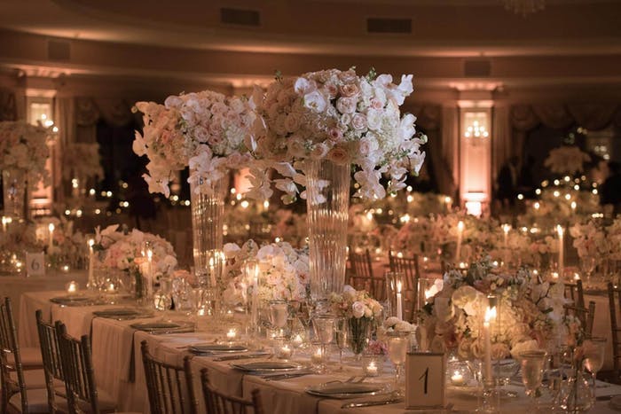 Dimly lit room with warm candles and white spherical white orchid wedding centerpieces