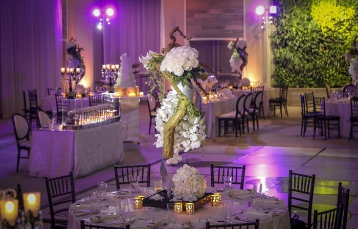 Purple lighting in the background with tall orchid wedding centerpieces