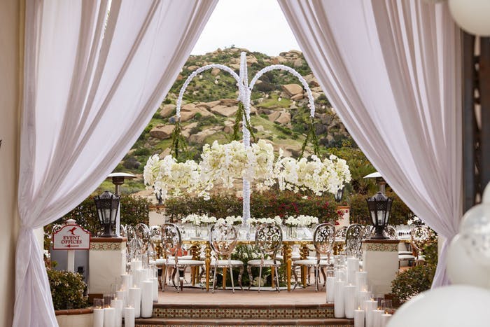 drapery leading to an archway and wedding reception table with white orchid wedding centerpieces