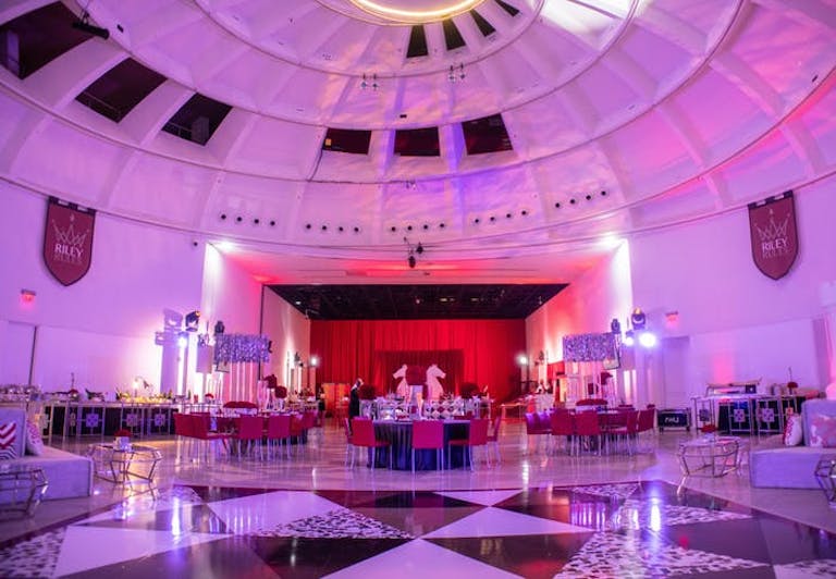 large circular ballroom with pink lighting and a red stage