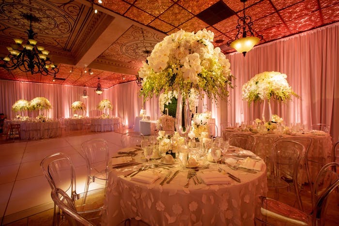 A glowing dimly lit room with yellow and warm white orchid wedding centerpieces.
