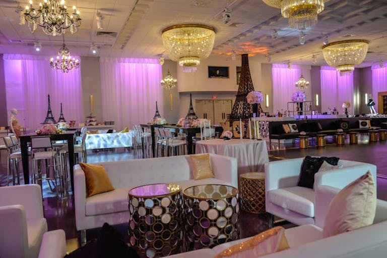 Lounge in the foreground with tables behind them. Walls are lit up purple