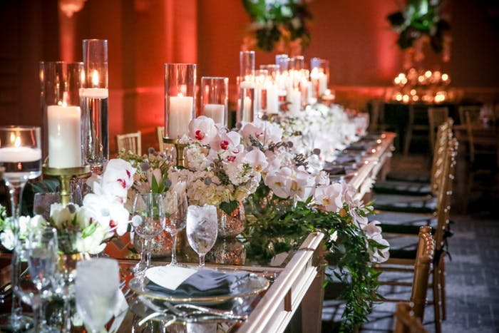 A red backdrop with pillar candles as centerpieces and orchids waterfalling off the table