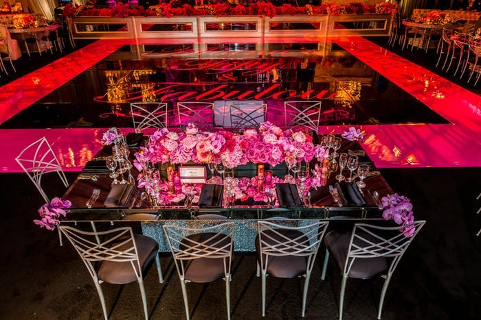 A Table with Pink Decor on the Outside of a Dance Floor with Pink Lighting | PartySlate