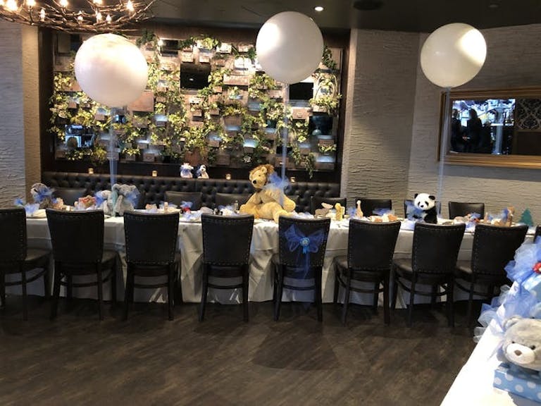Siena Tavern baby shower venue in Chicago with long rectangular table with three white balloons anchored by stuffed animals