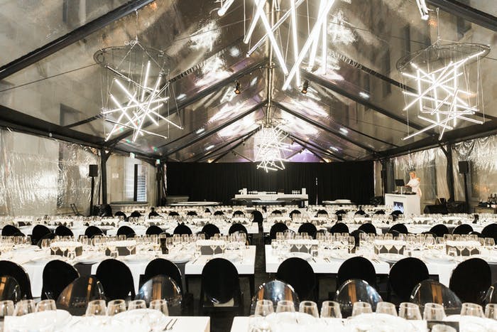 Casino-Themed Futuristic Party in Tent With White Linen, Black Chairs, and Geometric Neon Chandeliers | PartySlate