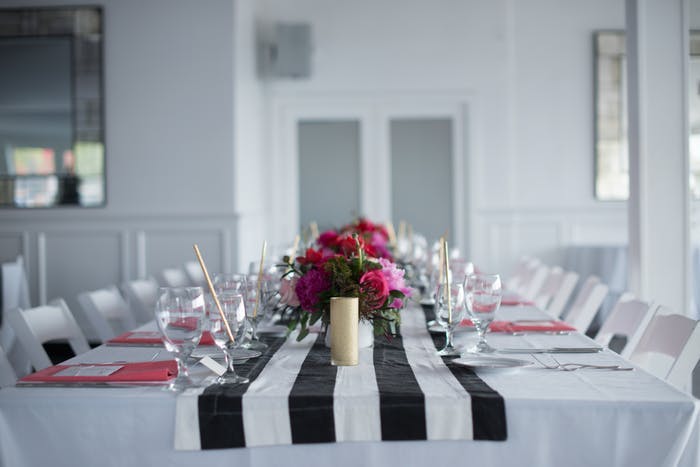 White Room With Table Decked in Black and White Striped Linen and Pink Centerpieces | PartySlate