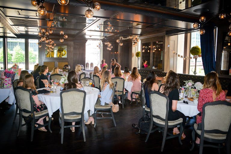 Prime and Provisions baby shower venue in Chicago with large room filled with large round tables with people and dangling chandeliers