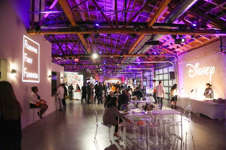 A big warehouse-like space with people walking around and graphics being shown on walls.