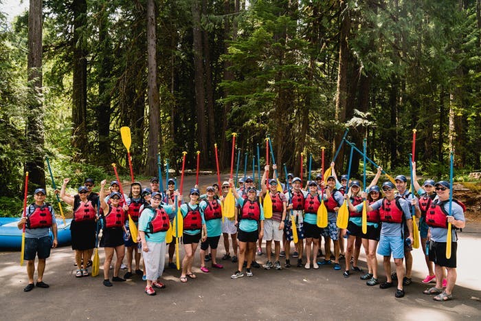 Guests at Oregon 50th Birthday Party Stand in Forest and Hold up Rowing Oars | PartySlate