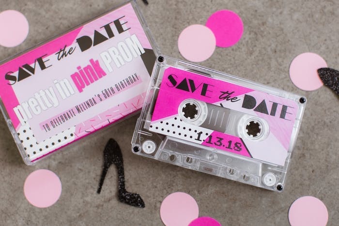 Two Cassette Tapes with Pink 'Save the Date' Printed on Them and Pink Confetti Surrounding | PartySlate