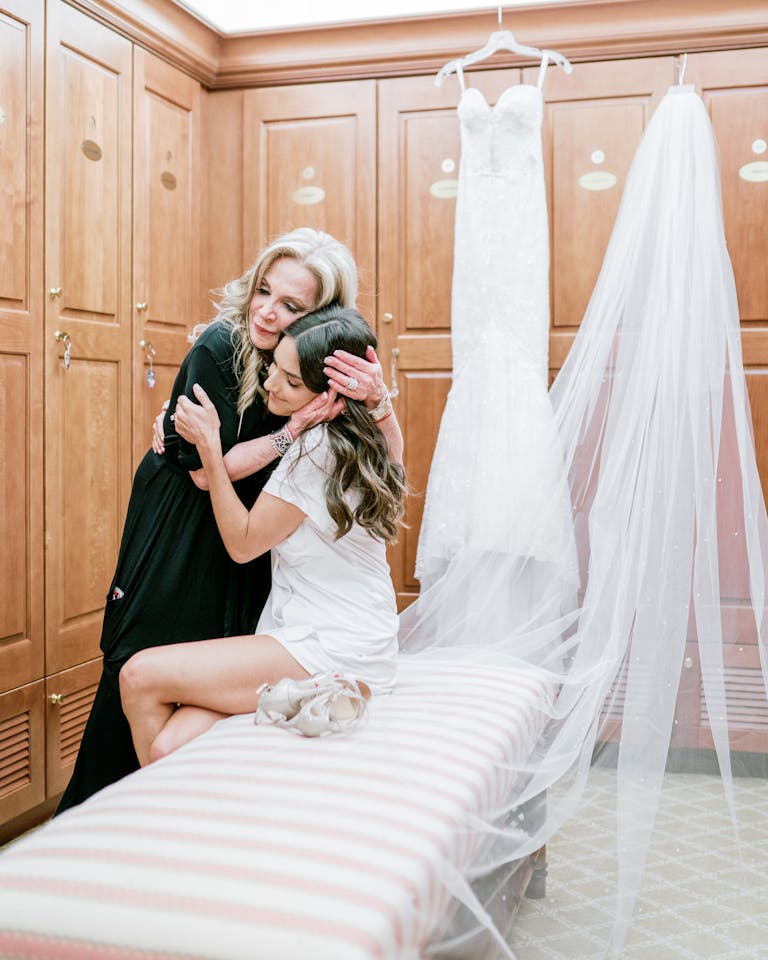 A daughter embraces her mother before putting on her bridal gown in the dressing room.