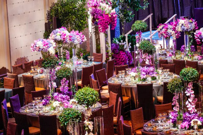 A room filled with purple and green florals on each round table