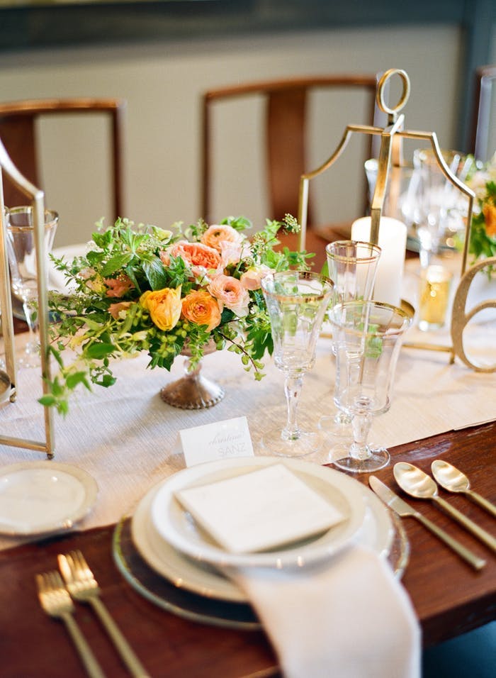 Toupe table runner with vintage metal accents in the forks and vase for the centerpiece holding coral flowers