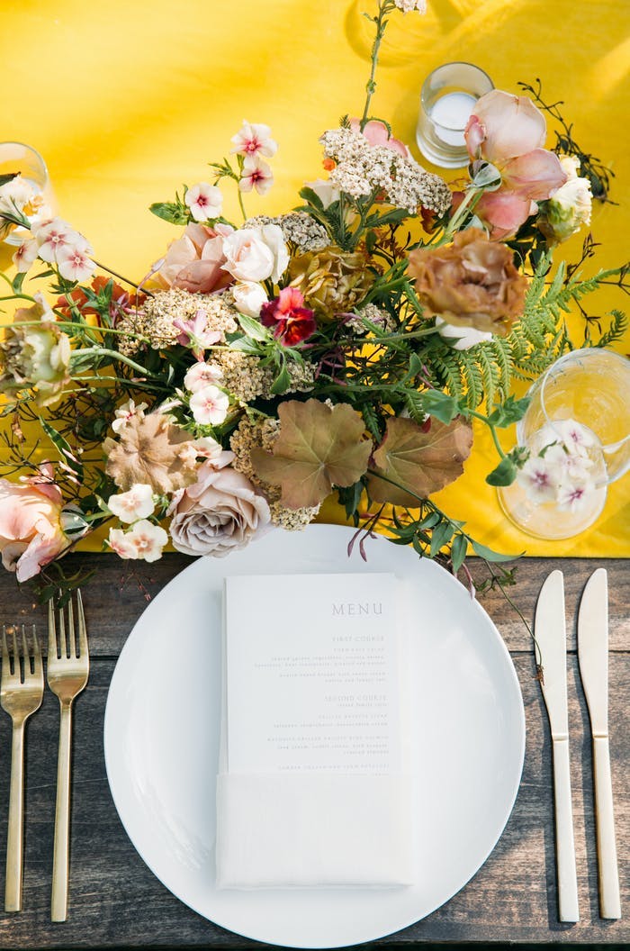 White plate with a bright yellow table runner and muted toned florals
