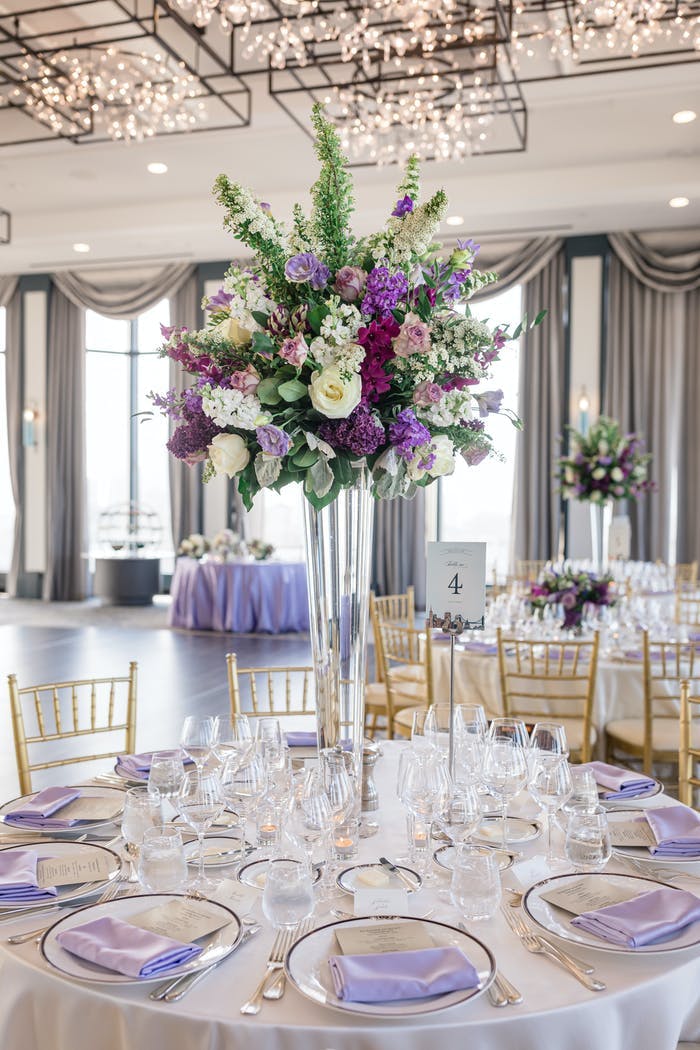 A white linened table with purple accents and tall centerpieces
