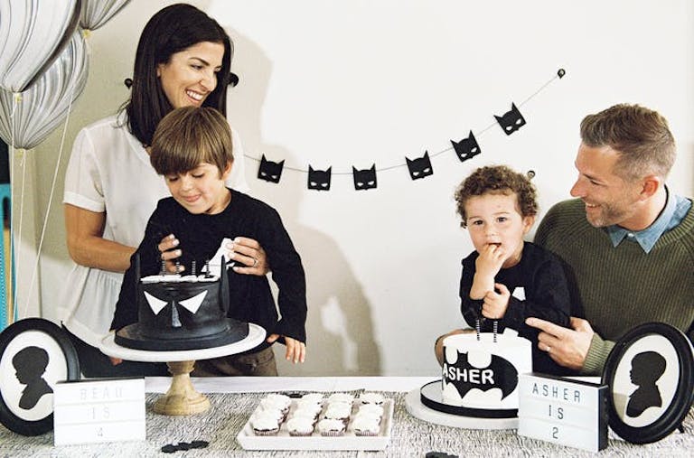 A mom, dad, and two little boys celebrate a joint Batman-themed birthday for their sons.