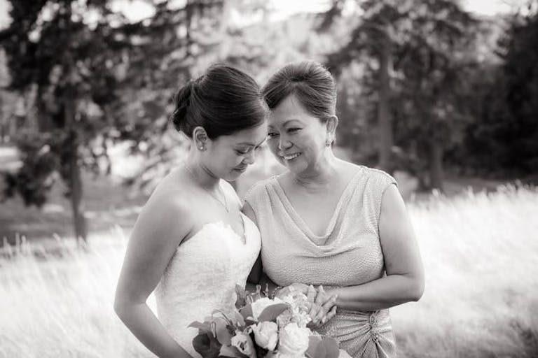 A black and white photo of a mother and daughter outside in a meadow embracing each other