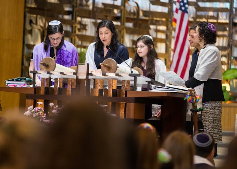 A mom reads Torah at the Bimah with her son and daughter.