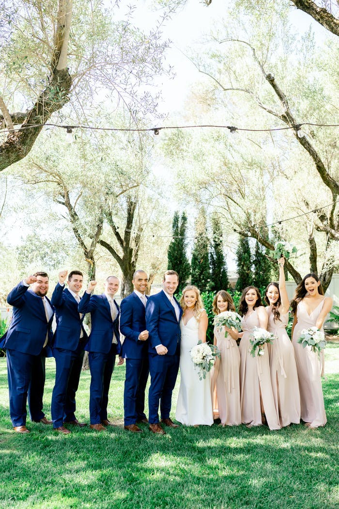 bridal party and groomsmen underneath the trees and fairy lights