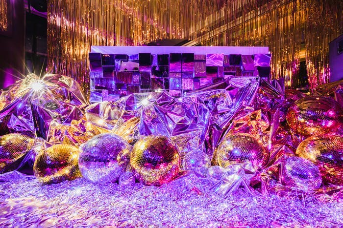 Disco balls and glitter make up the background of a photo op for Disco-themed party | PartySlate