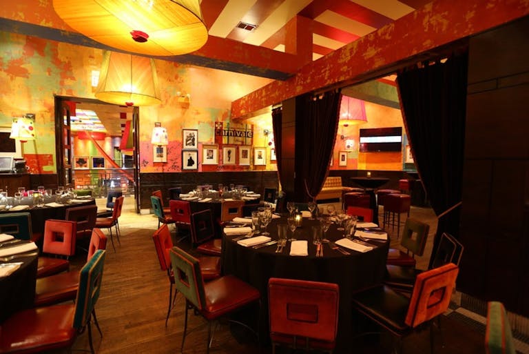 Private dining space in bright bold colors with exposed wooden beams and drum chandeliers.