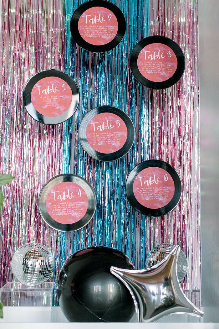 pink and black compacts on top of shiny drape linens for disco theme party | partySlate