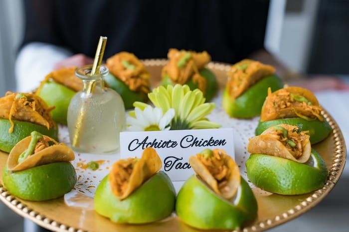 appetizer tray holding mini tacos wedged between limes