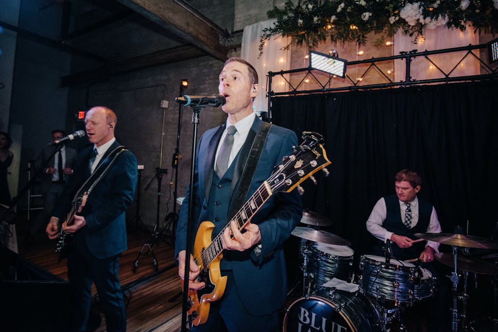 Two guitarists and drummer perform in a raw industrial space.
