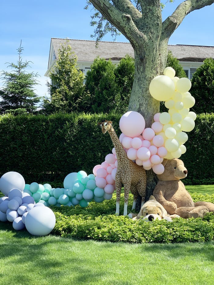 A balloon installation that goes from the ground up a tree and over a toy giraffe