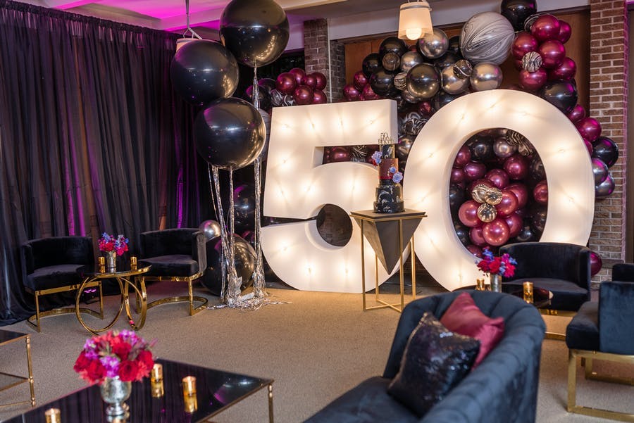 a photo background with a 50 illuminated and pink balloons in the back and sides