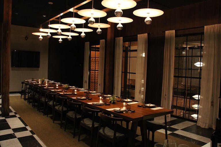 Dimly lit private dining space with banquet table and globed lighting.