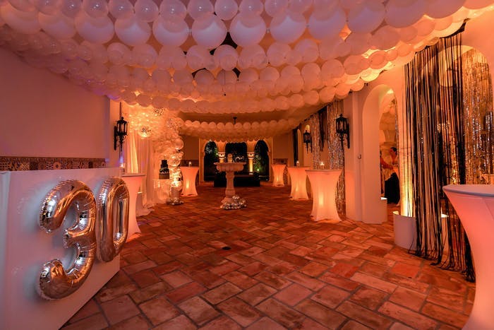 A wide hallway with golden lighting and white balloons strung across the ceiling