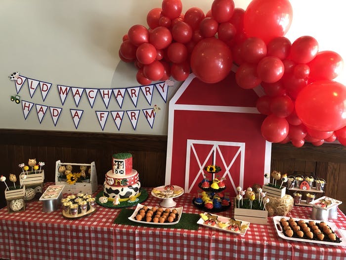 A dessert table with red balloons, a red bar and checkered table linen
