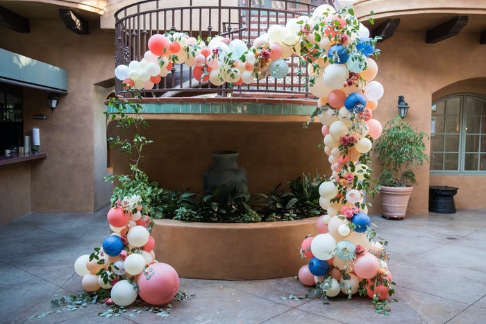 a balcony that jets out onto a walk way covered with balloons