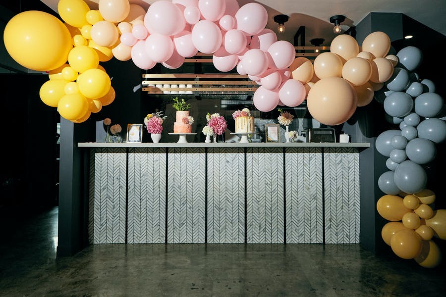 A dessert table with a balloon arch of changing colors.