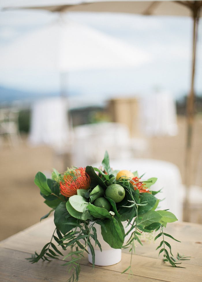limes and greenery in a white pot on top of a light brown table